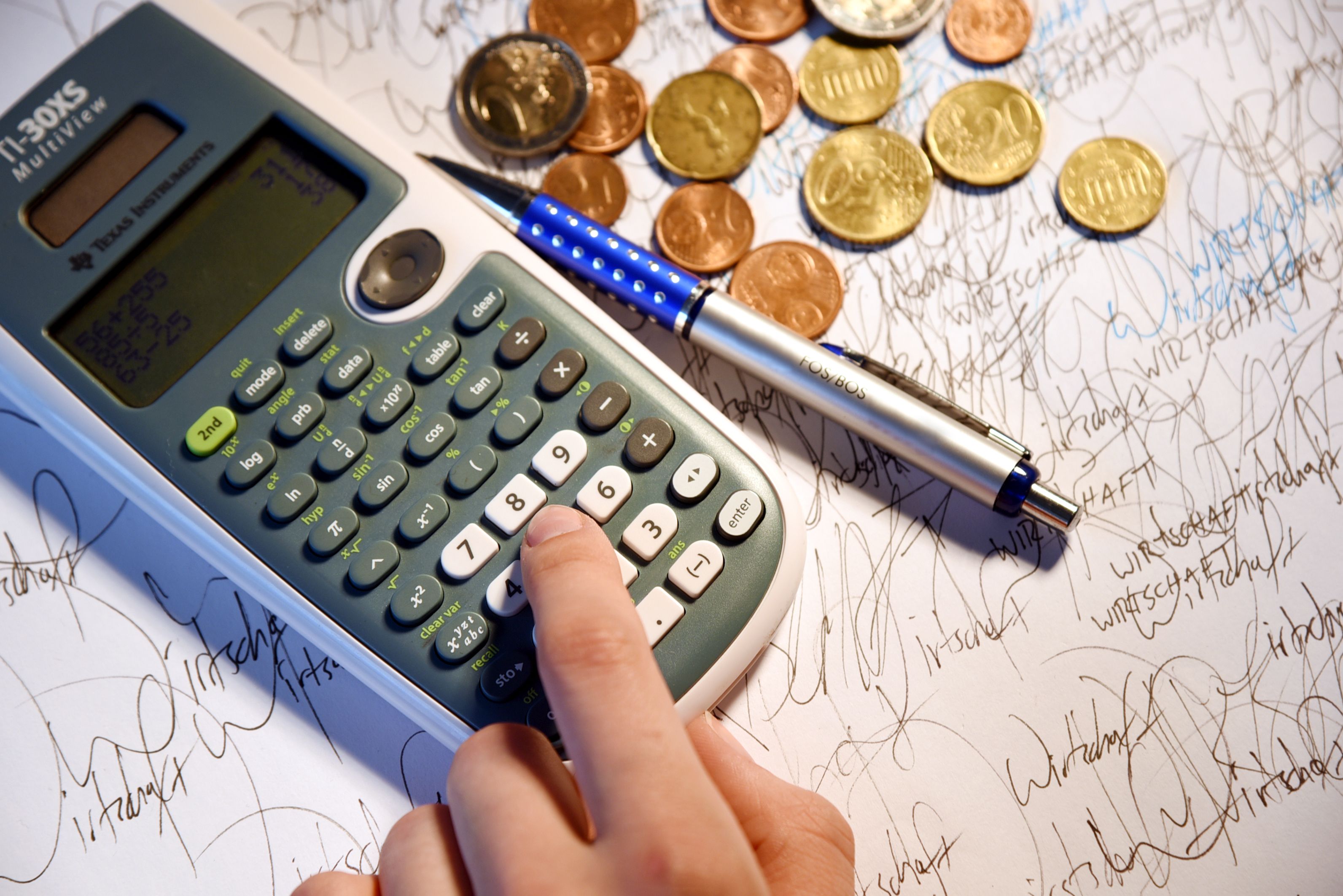 Taschenrechner, Münzen und Stift als Symbol für wirtschaftliche Berechnungen